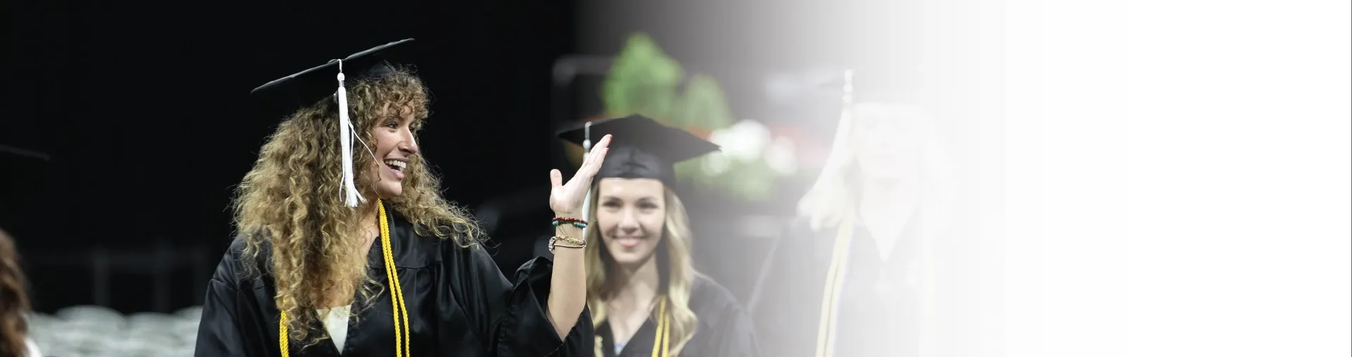 Graduate waving during commencement ceremony.